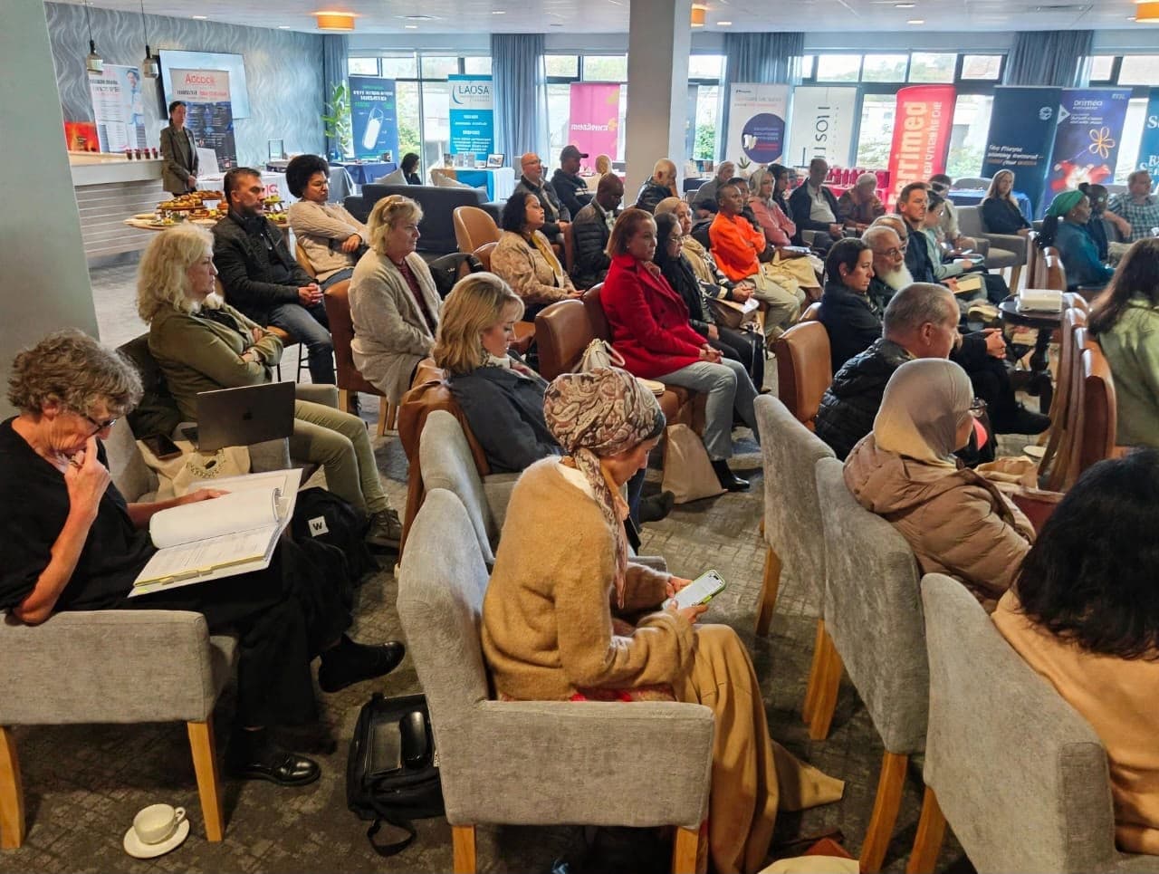 Healthcare professionals attending a MedTalk Network event, with partner exhibition banners in the background