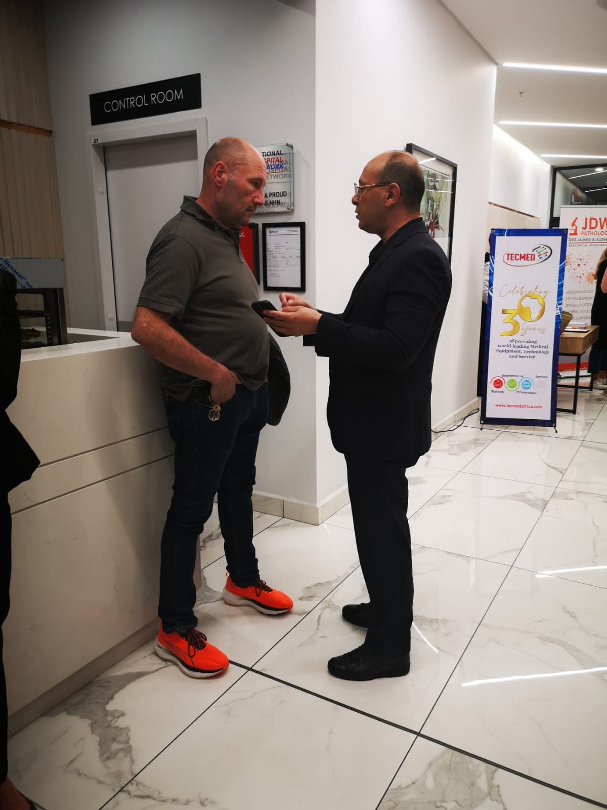Two healthcare professionals in conversation near exhibitor banners at a MedTalk Network event